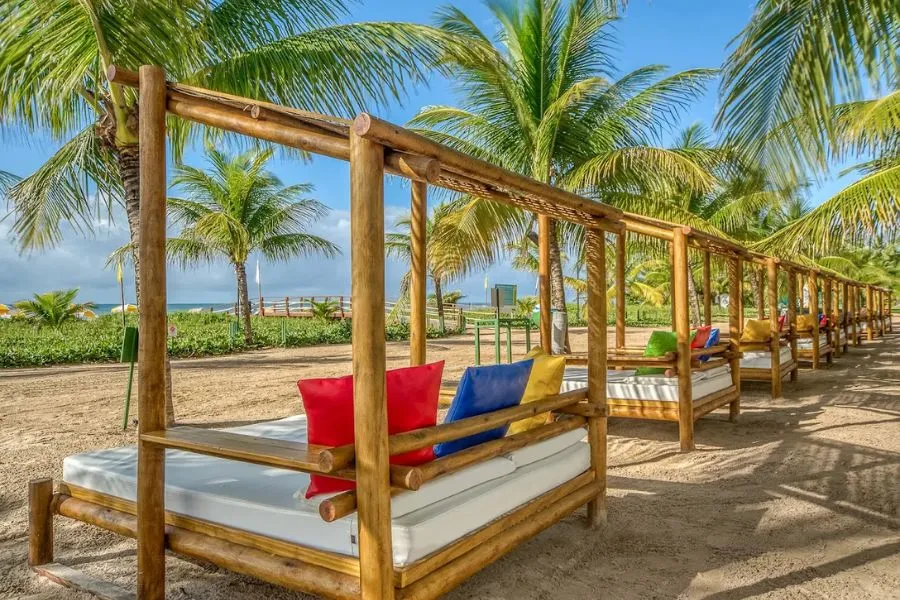 Gazebos elegantes à beira do rio, rodeados por palmeiras e vegetação tropical no Salinas Maragogi All Inclusive Resort, proporcionando um espaço de descanso e contemplação em meio à natureza