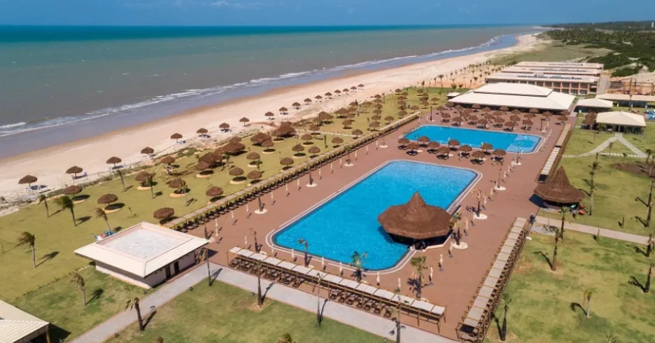resort-vila-gale-touros-piscina-vista-aerea-beira-mar-rio-grande-do-norte-900×600 Vista aérea de resort à beira-mar com piscinas e espreguiçadeiras.